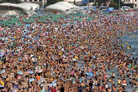 The NO.1 Bathing Beach in east China's Shandong Province is packed with visitors Saturday, July 22, 2006. With the arrival of a travel season, bathing beaches in the city have become a hot cake with tourists. [Xinhua]